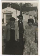 Three people outside the Gospel Church of God