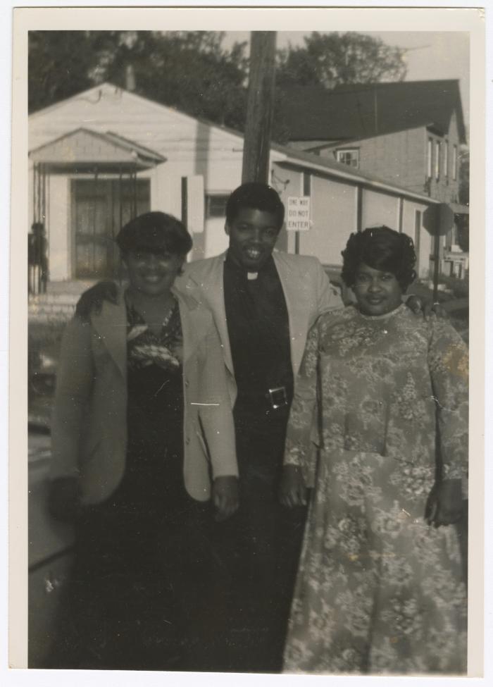 Three people outside the Gospel Church of God