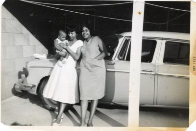 Two women and a baby posing by a car