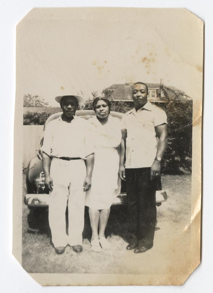 Woman and two men standing by a car