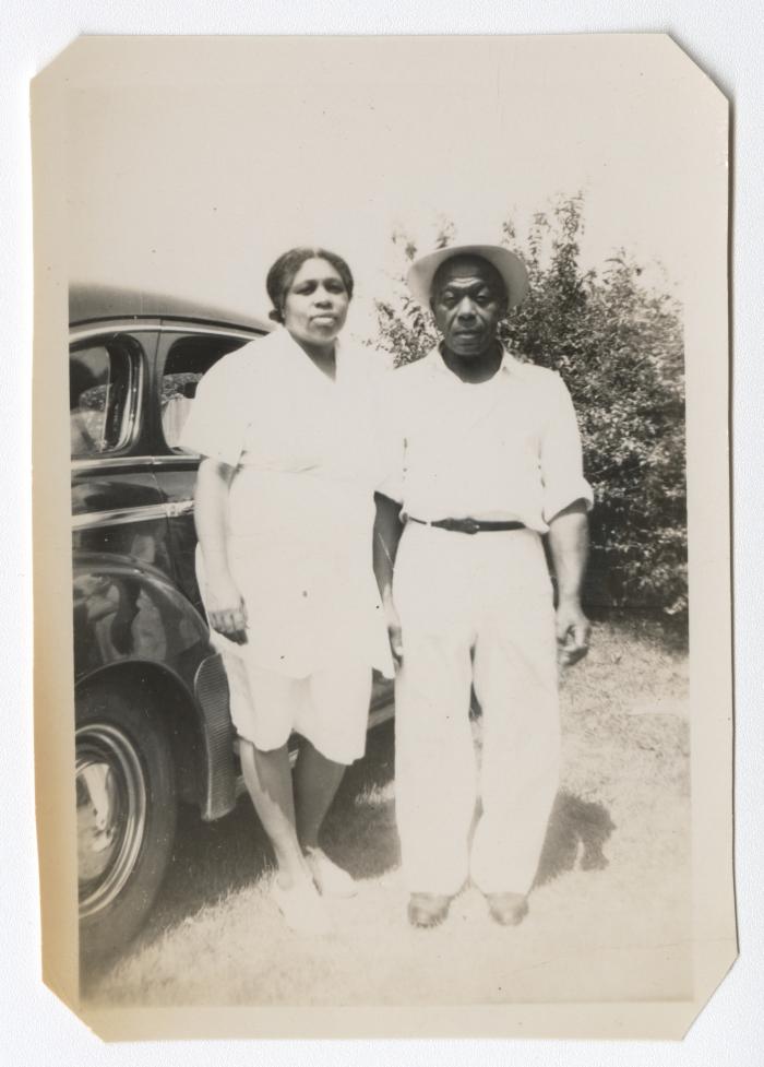 Man and woman standing next to an automobile