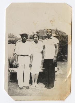 Woman and two men standing by a car