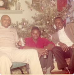 Three men sitting by a Christmas tree