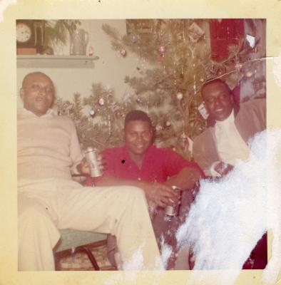 Three men sitting in front of the Christmas tree