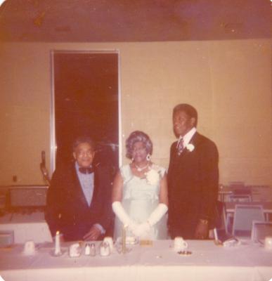 Two men and a woman standing behind a banquet table