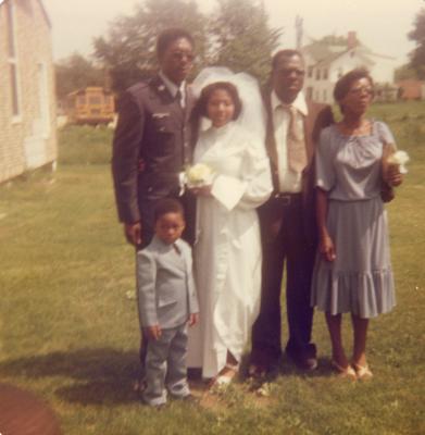 Man, woman, and child posing with newlyweds