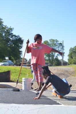 Young girls painting a street mural 