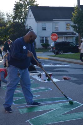 Man painting a green "N" for the Black Lives Matter street mural