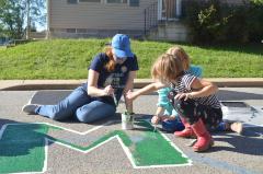 Woman and two young girls painting a Black Lives Matter street mural
