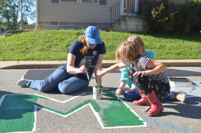 Woman and two young girls painting a Black Lives Matter street mural