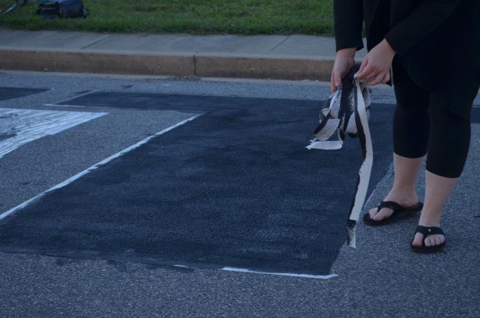 Peeling the tape off the "T" of the Black Lives Matter street mural