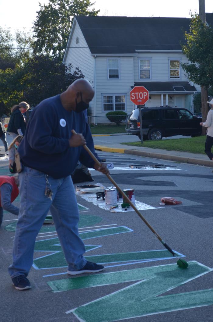 Man painting a green "N" for the Black Lives Matter street mural