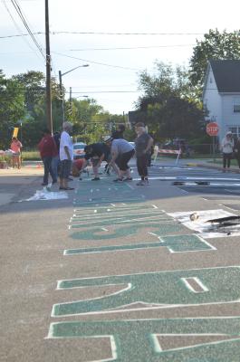 Pulling the tape off of the green letters of the Black Lives Matter street mural