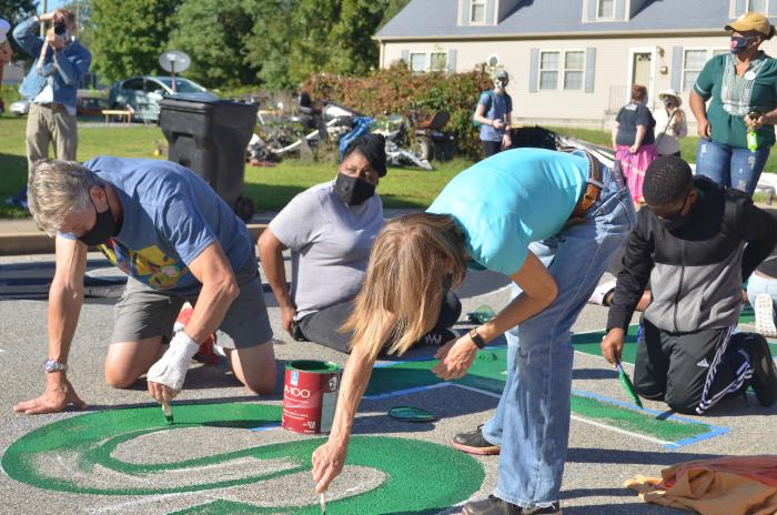 Man and woman painting the "S" of the Black Lives Matter street mural