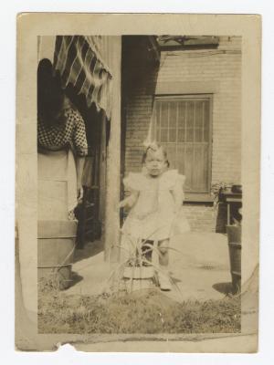 A young child in front of a brick building