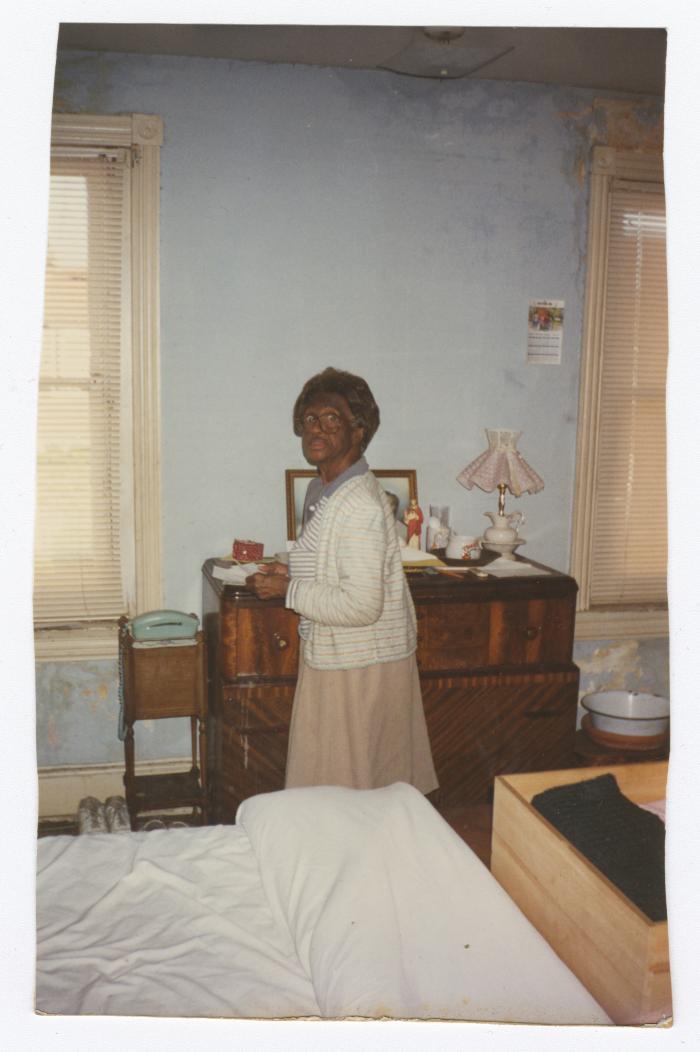 Elderly woman standing in front of dresser
