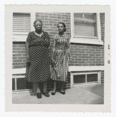 Two women standing outside on the sidewalk