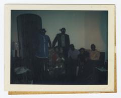 Five adults and two children in a dark lit room