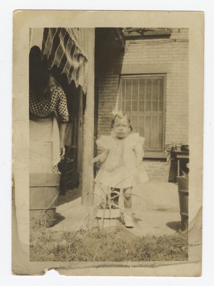 A young child in front of a brick building