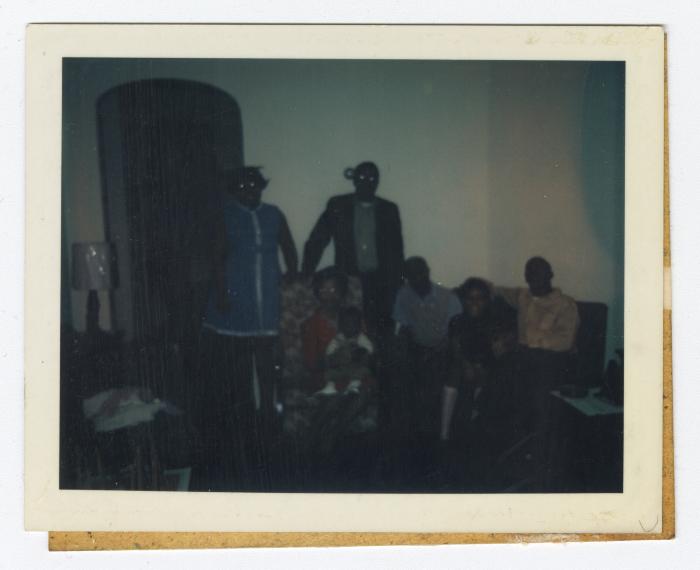 Five adults and two children in a dark lit room