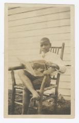 A young boy reading in a wooden chair