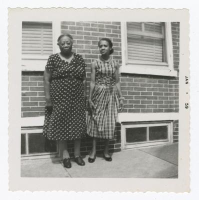 Two women standing outside on the sidewalk