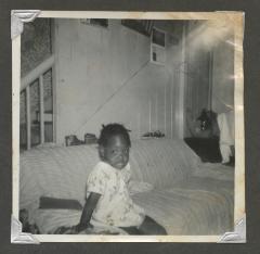 A young girl in a floral dress sitting on a couch