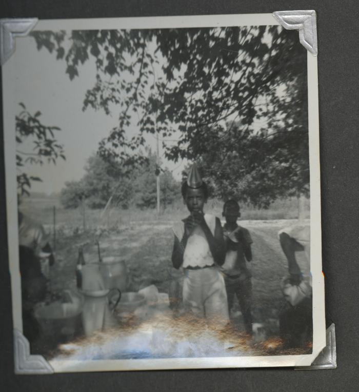 Two young children standing at an outdoor birthday celebration
