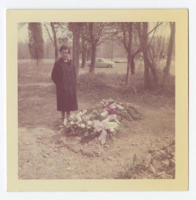 A woman next to a grave covered in flowers