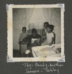 Three children and a baby around a woman reading