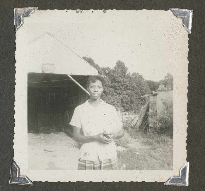 A woman standing in front of a dilapidated structure