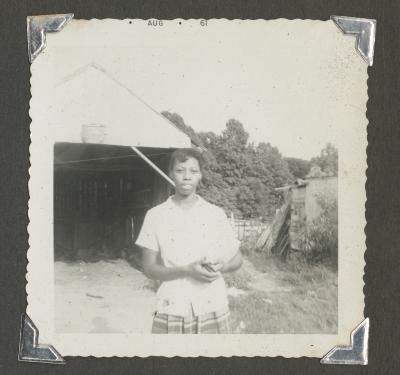 A woman standing in front of a dilapidated structure