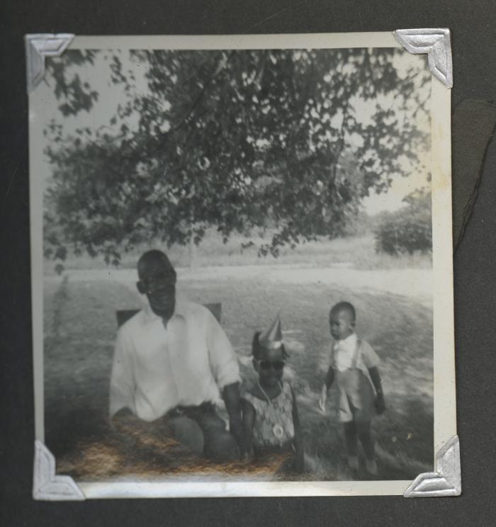 An older man sitting outside with two children