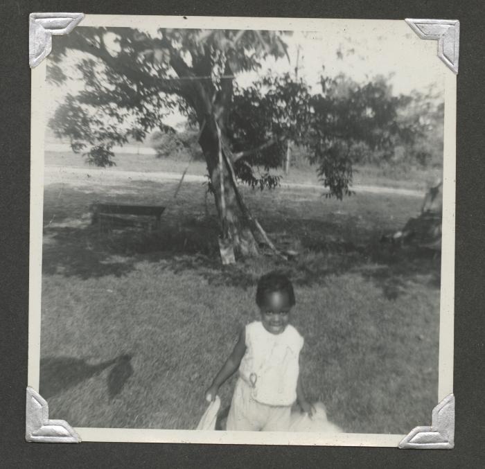 A young girl standing in front of a tree