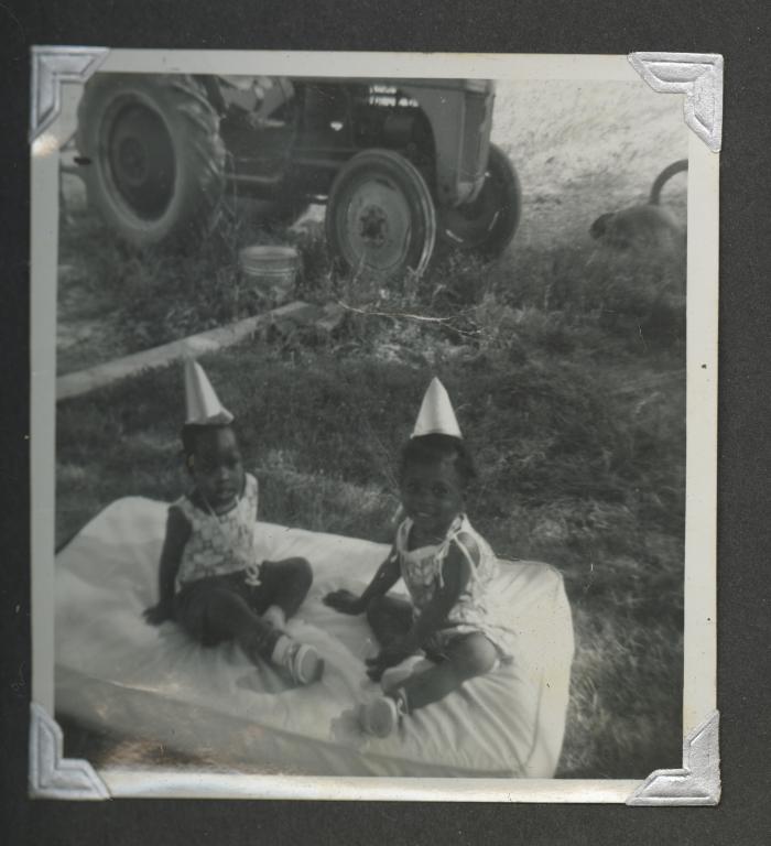 Two young girls in matching outfits on a small mattress