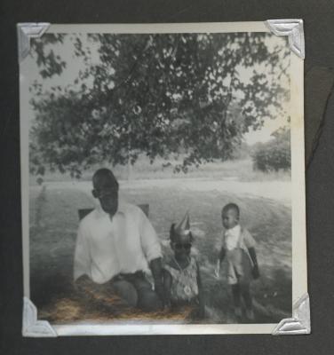 An older man sitting outside with two children