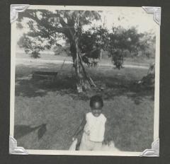 A young girl standing in front of a tree