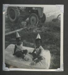 Two young girls in matching outfits on a small mattress