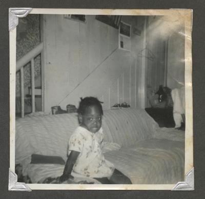 A young girl in a floral dress sitting on a couch