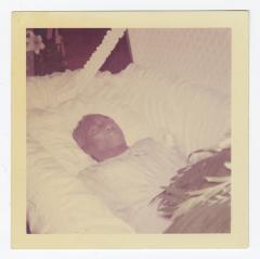 A deceased man in an open casket