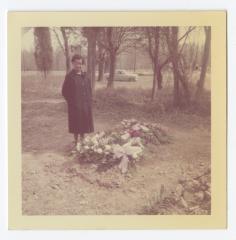 A woman next to a grave covered in flowers