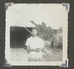 A woman standing in front of a dilapidated structure