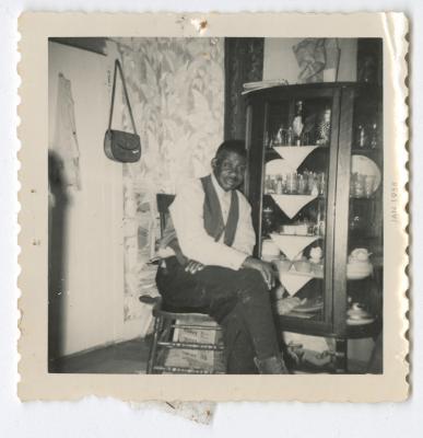 A man sitting next to a China cabinet 