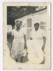 Two women standing outside a house
