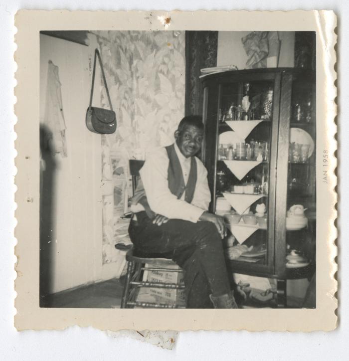 A man sitting next to a China cabinet 