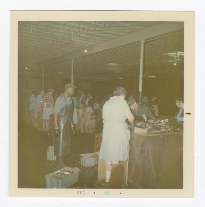 Women working in the fish department at VITA Foods. Sydney Caulk is standing beside the tubs of fish.