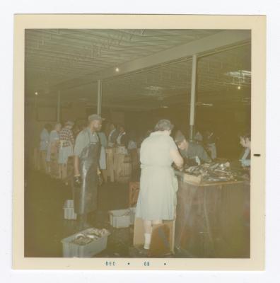 Women working in the fish department at VITA Foods. Sydney Caulk is standing beside the tubs of fish.