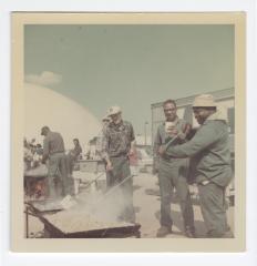 Sam Wright, two unknown men, Leon Reese, and Caramel Jones preparing food for a cookout at VITA Foods