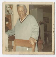 An older woman with her hand on a chair 