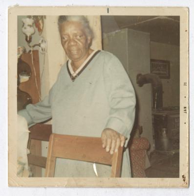 An older woman with her hand on a chair 